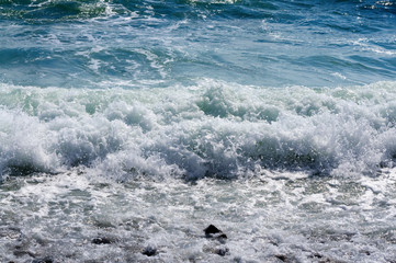 Fototapeta premium The sea waves rolling on the stony coast, a close up