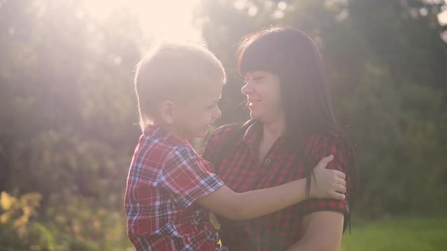 happy family mother's day funny the nature slow motion video teamwork outdoors. mom girl holds son boy in arms smiling sunlight lifestyle cute video care. mother andson circling friendly cuddle family