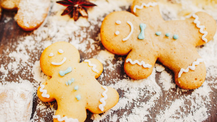 Traditional winter holidays pastry. Closeup of homemade gingerbread man cookies on table with flour.
