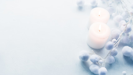 Romantic winter interior decor. Closeup top view of white candles and fluffy floral ornament on frost background. Copy space.