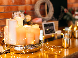 Romantic home decoration. Arrangement of fairy lights and candles over blur brick wall background.