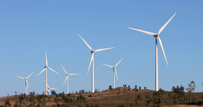 Alternative energy sources. Large blades of wind turbines in rotation with the blue sky in the background - aerial view with a drone - environment & ecological concept