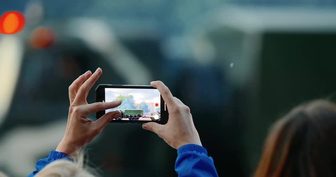 Woman hand with smartphone shoots war parade. Military vehicle in camouflage with a machine gun on the roof. Independence Day military parade in the CIS country. Urban life. Belarus 3 July 2019.