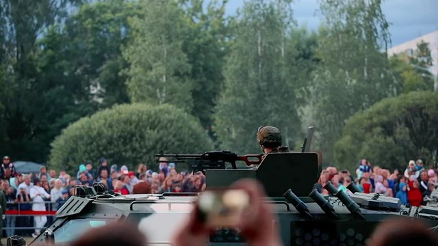 Military equipment and armored car in a crowd of people. War vehicle in camouflage with a machine gun on the roof. Independence Day military parade in the CIS country. Urban life. Belarus 3 July 2019.