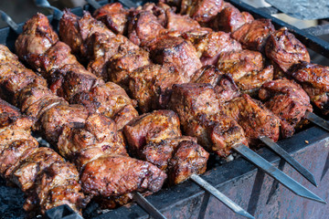 Grilled kebab cooking on metal skewer closeup. Roasted meat cooked at barbecue. BBQ fresh beef meat chop slices. Traditional eastern dish, shish kebab