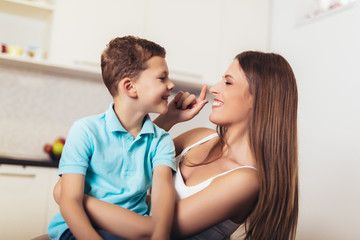 Happy family mother and child son hugging in kitchen