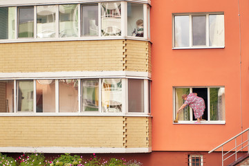 woman washes a window while standing on a windowsill