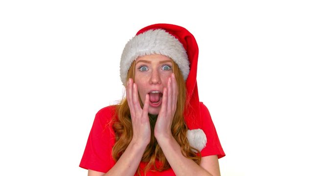 Suprised woman in Stanta Claus hat standing with shock on her face on white background.