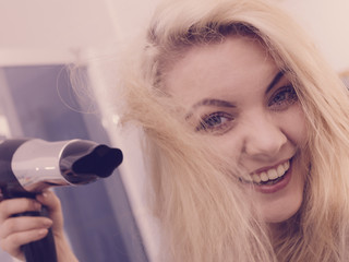 Woman drying hair in bathroom