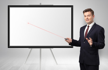 Young businessman with laser pointer and copyspace white wall