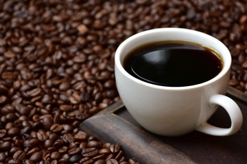 Obraz na płótnie Canvas Cup of hot coffee on coffee beans