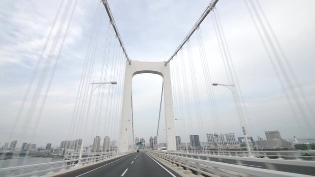 Driving shot on a bridge, going under a large arch. This bridge is found in Japan. 
