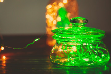 Green garland with light bulbs put in glass storage jar
