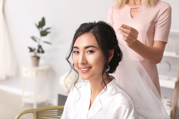 Fototapeta premium Professional hairdresser working with young Asian bride at home