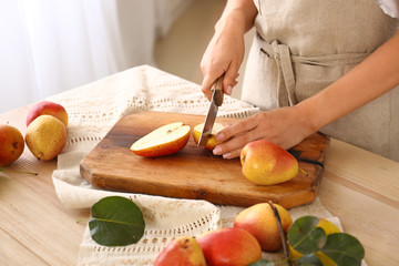 Woman cutting ripe pears in kitchen