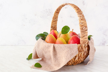 Basket with tasty fresh pears on light background