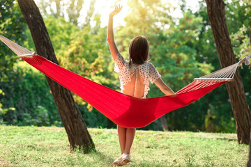 Happy young woman sitting in hammock outdoors