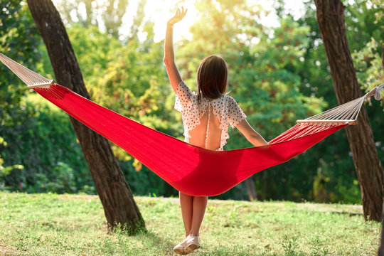 Happy young woman sitting in hammock outdoors