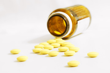 Yellow Pills Scattered Out of a Pill Bottle, Close up view