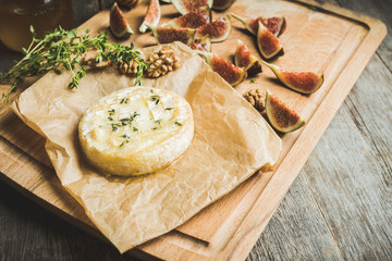 Baked camembert cheese with figs, walnuts, honey and thyme on the rustc background. Selective focus. Shallow depth of field.