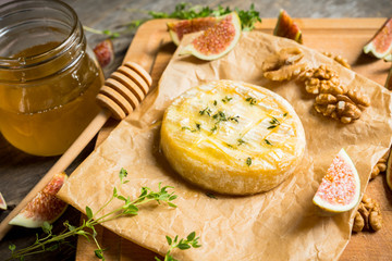 Baked camembert cheese with figs, walnuts, honey and thyme on the rustc background. Selective focus. Shallow depth of field.