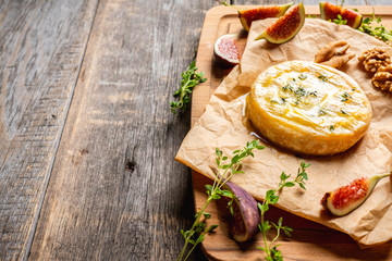 Baked camembert cheese with figs, walnuts, honey and thyme on the rustc background. Selective...