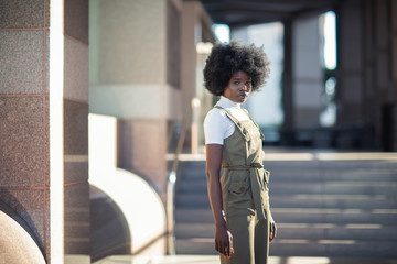 Fashionable African American girl in downtown wearing fancy overalls and white turtleneck