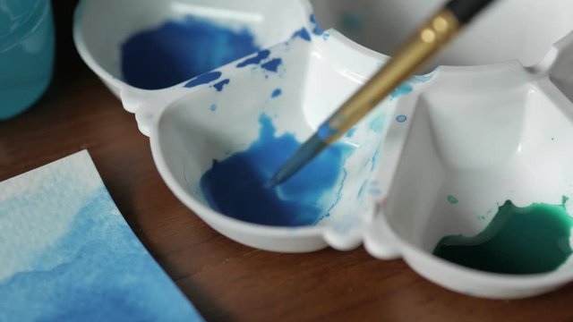 Painter dips the brush into the palette