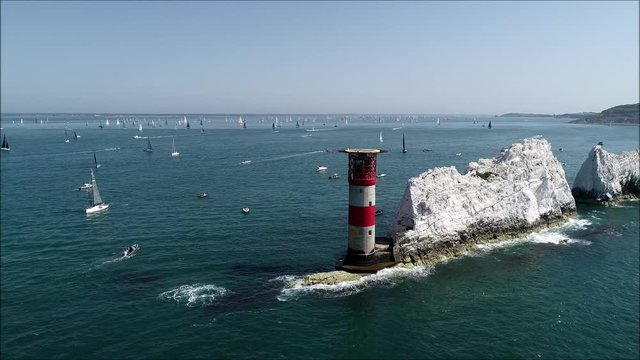 The Needles, cliffs and lighthouse shot with sailing yachts in the background. Drone shot.