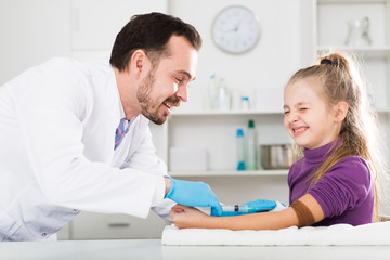 Male doctor injecting little patient