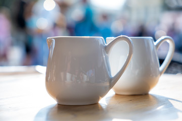 Two white cups of coffee on a table of outdoor cafe.