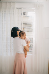 Portrait of happy vietnamese mother hugging with her cute little daughter at home