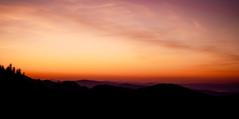 Romantic purple and orange sunset over the high Tatra mountains with dense mist and long sun rays