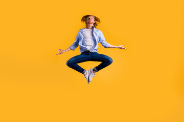 Full size photo of redhead guy jumping high meditating exercise holding body in lotus position wear casual trendy outfit isolated yellow background