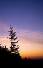 Obraz na płótnie Canvas Romantic purple and orange sunset over the high Tatra mountains with dense mist and long sun rays