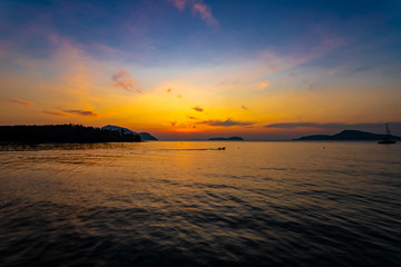 Fototapeta premium Silhouette of a boat passing over the ocean at sunrise.