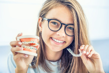 Dental invisible braces or silicone trainer in the hands of a young smiling girl. Orthodontic concept - Invisalign - obrazy, fototapety, plakaty