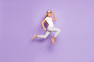 Fototapeta na wymiar Hurry to start new day. Full size profile side photo of cheerful kid jump run have fun on weekends slumber party wear white t-shirt pants barefoot isolated over purple violet color background