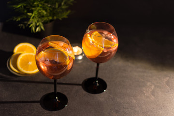 Two glasses of aperol spritz cocktail with orange slices on black background.