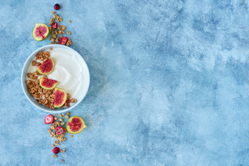 Obraz na płótnie Canvas Granola with yogurt and berries for healthy breakfast. Bowl of greek yogurt with granola and fresh fig and dried berries, top view, copy space. 