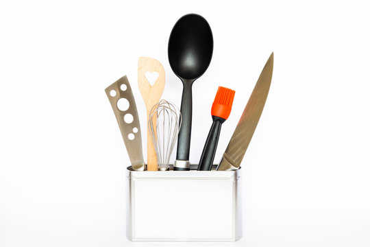 Assortment of kitchenware and cooking tools in a square silver colored metal box with copy space on white background