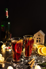 Mulled wine with slice of orange, apples and spices on christmas background with different decorations. Hot christmas drink.