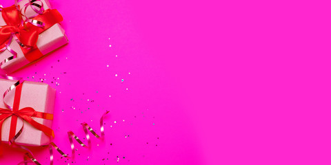 Christmas gifts paper boxes with red satin ribbon and golden shiny decor on a pink background