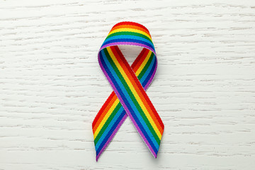 LGBT rainbow ribbon pride symbol. Stop homophobia. White wood background