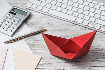 Businessman workspace at desk with red paper ship