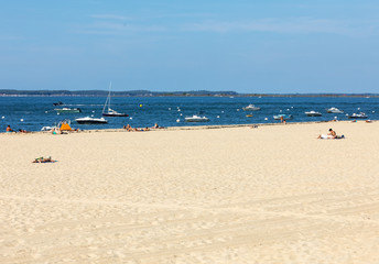 Fototapeta na wymiar People are enjoying a sunny day on a sandy beach in Arcachon, France