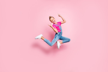 Fototapeta na wymiar Full length body size photo stylish trendy cute cheerful rejoicing girl wearing jeans denim overall t-shirt fuchsia jumping showing rock sign isolated over pink pastel color background