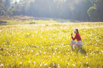 Hipster Asian woman in red and sunglasses on white flower and grass field
