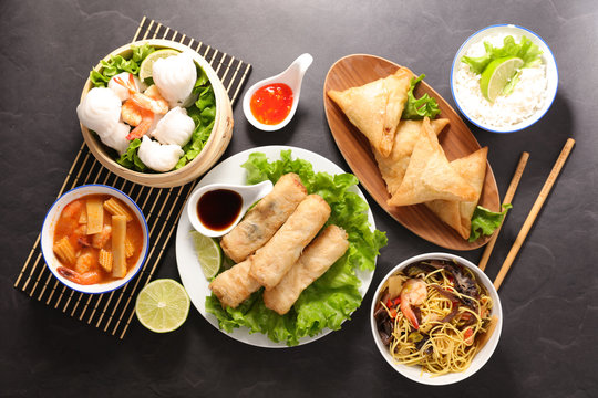 selection of asian food- spring roll, samosa, fried noodles, soup, rice and dumpling