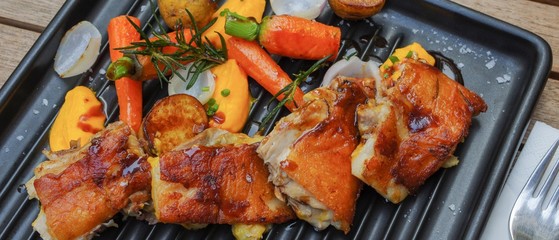 Chicken bbq with small baby carrots, potatoes, rosemary, garlic and mango sauce on black iron oven tray